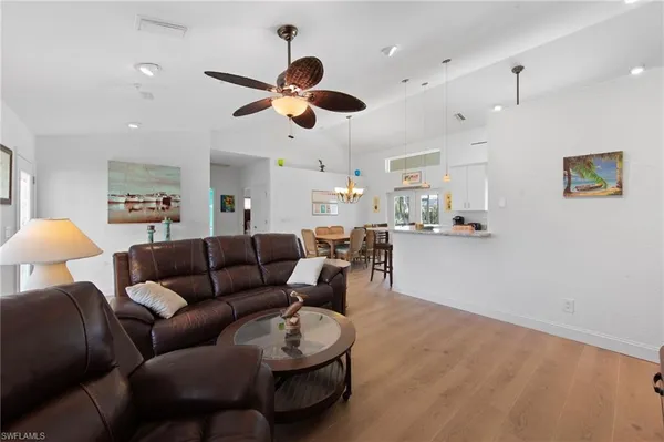 a living room with furniture kitchen view and a chandelier
