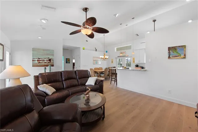 a living room with furniture kitchen view and a chandelier