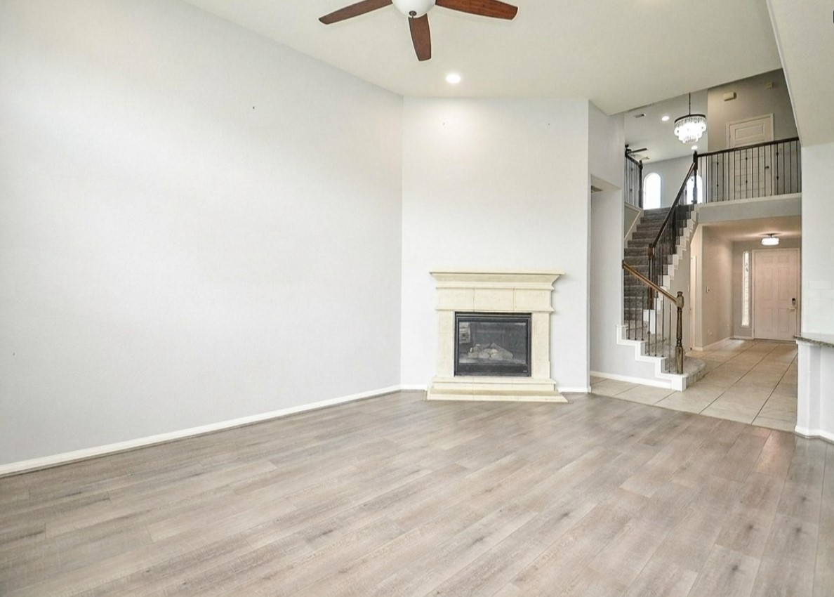 7042 Sliding Rock Circle Spring, TX 77379 - Photo 8 of 36 Spacious living room with elegant fireplace, high ceilings, and beautiful flooring, leading to an inviting staircase.
