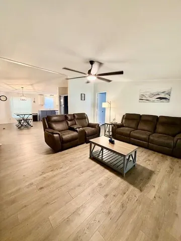 a living room with stainless steel appliances furniture a chandelier and kitchen view