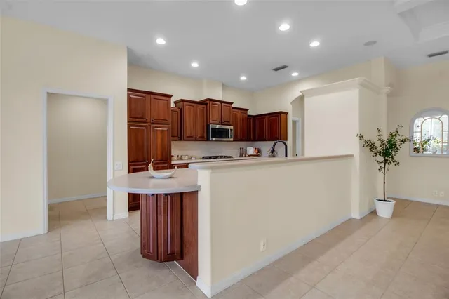 a kitchen with kitchen island granite countertop stainless steel appliances a sink a counter top space and cabinets