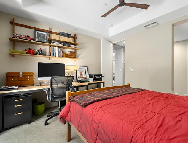 a bedroom with a bed and a computer on a desk