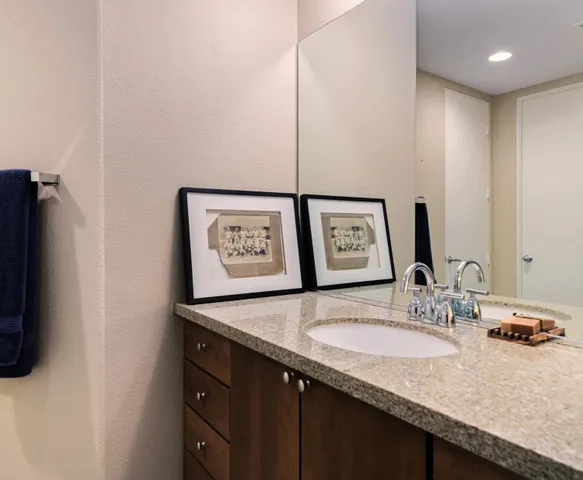 a bathroom with a granite countertop sink and a mirror