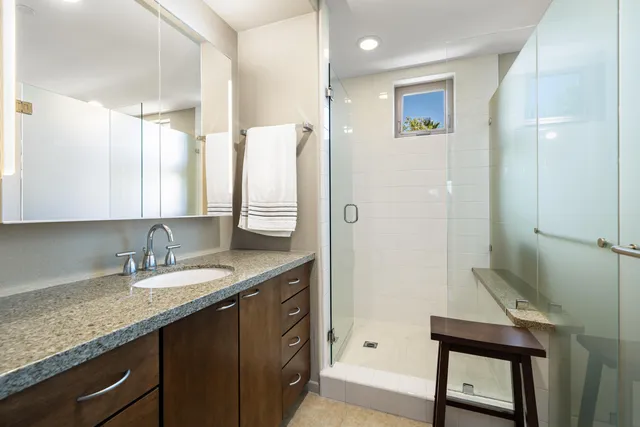 a bathroom with a granite countertop sink a mirror and a shower