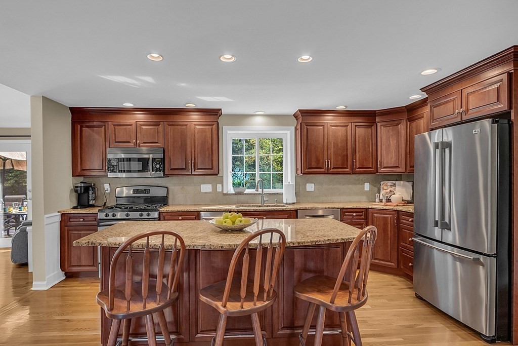 27 Sable Run Lane Methuen, MA 01844 - Photo 8 of 42 a kitchen with stainless steel appliances granite countertop a stove a sink a refrigerator cabinets and a dining table with wooden floor