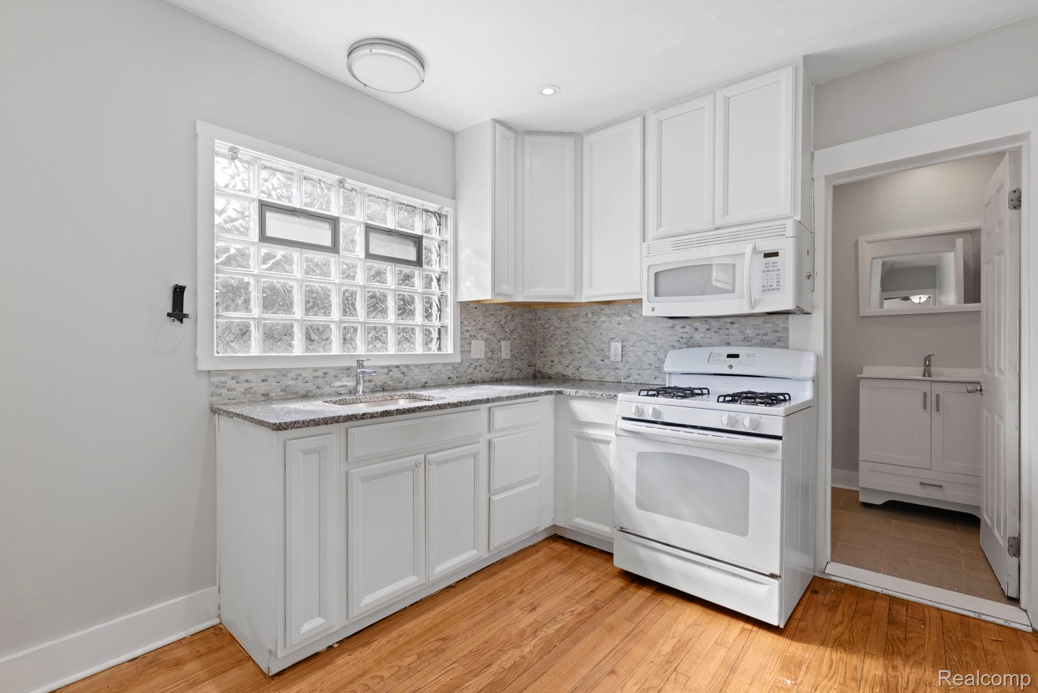 74 Pine Street River Rouge, MI 48218 - Photo 8 of 28 Kitchen with white appliances, white cabinetry, backsplash, and light wood-type flooring