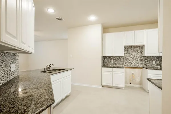 a kitchen with granite countertop white cabinets and white appliances