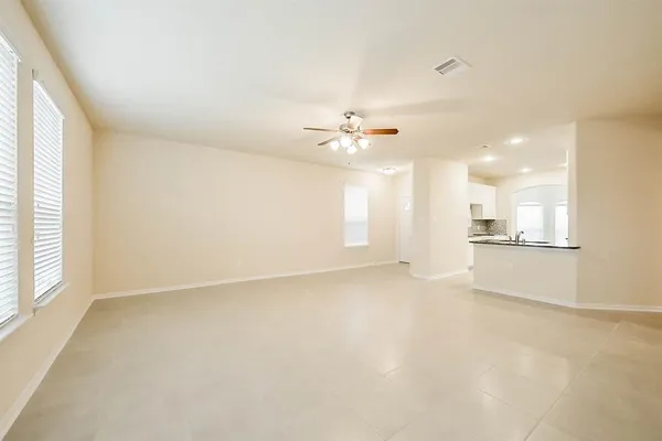 an empty room with a kitchen and a ceiling fan