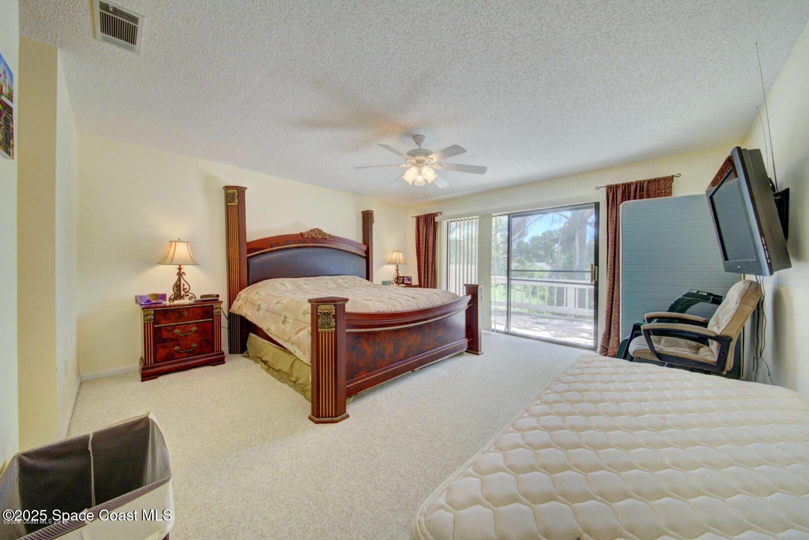 227 Augusta Way Melbourne, FL 32940 - Photo 20 of 35 a spacious bedroom with a bed and a flat tv screen