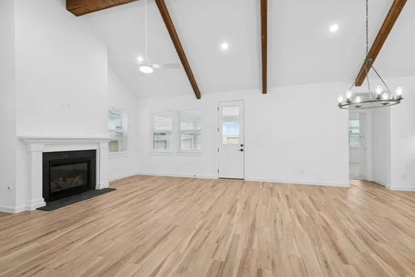 an empty room with wooden floor fireplace and windows