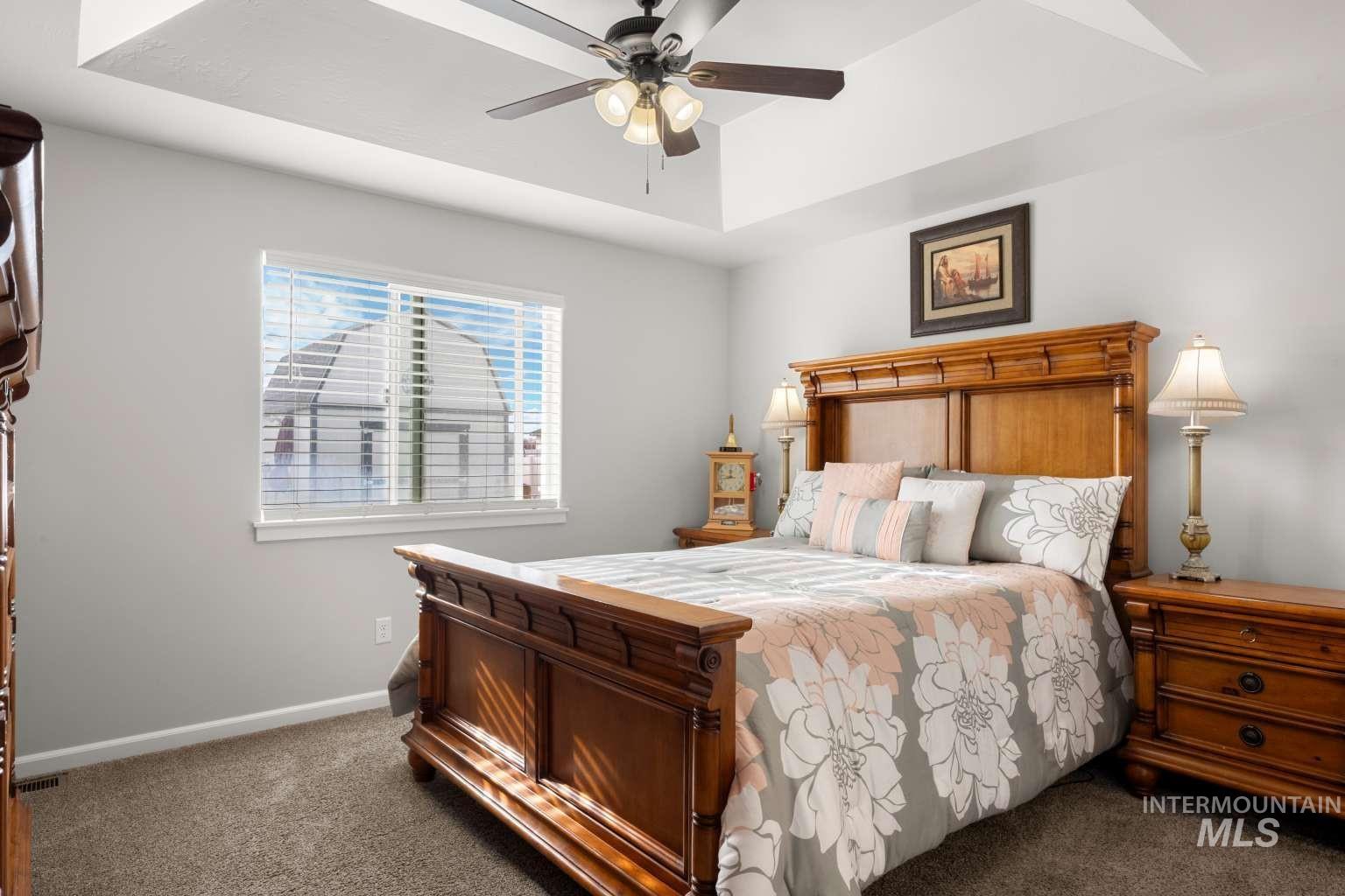 521 East 15th Street Rupert, ID 83350 - Photo 12 of 21 Carpeted bedroom featuring ceiling fan and a tray ceiling