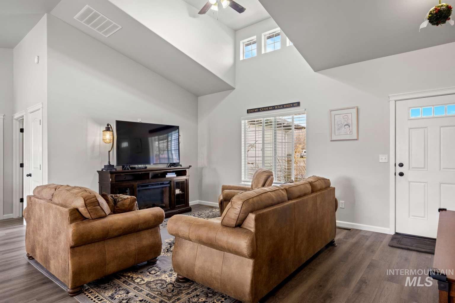 521 East 15th Street Rupert, ID 83350 - Photo 9 of 21 Living room featuring a towering ceiling, a ceiling fan, dark wood-style flooring, and plenty of natural light