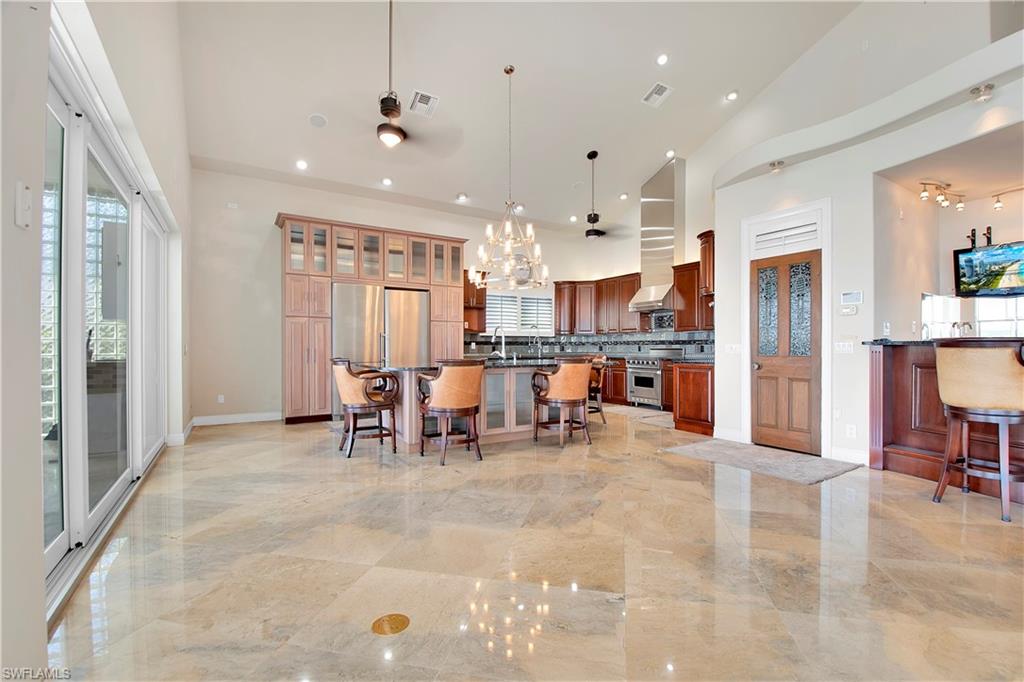 28 West Pelican Street Naples, FL 34113 - Photo 7 of 50 a view of kitchen with kitchen island granite countertop cabinets and refrigerator