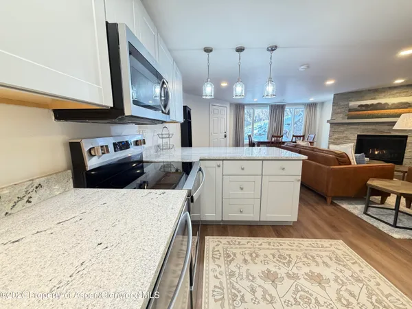 a large kitchen with stainless steel appliances kitchen island granite countertop a refrigerator a stove a sink dishwasher and white cabinets with wooden floor