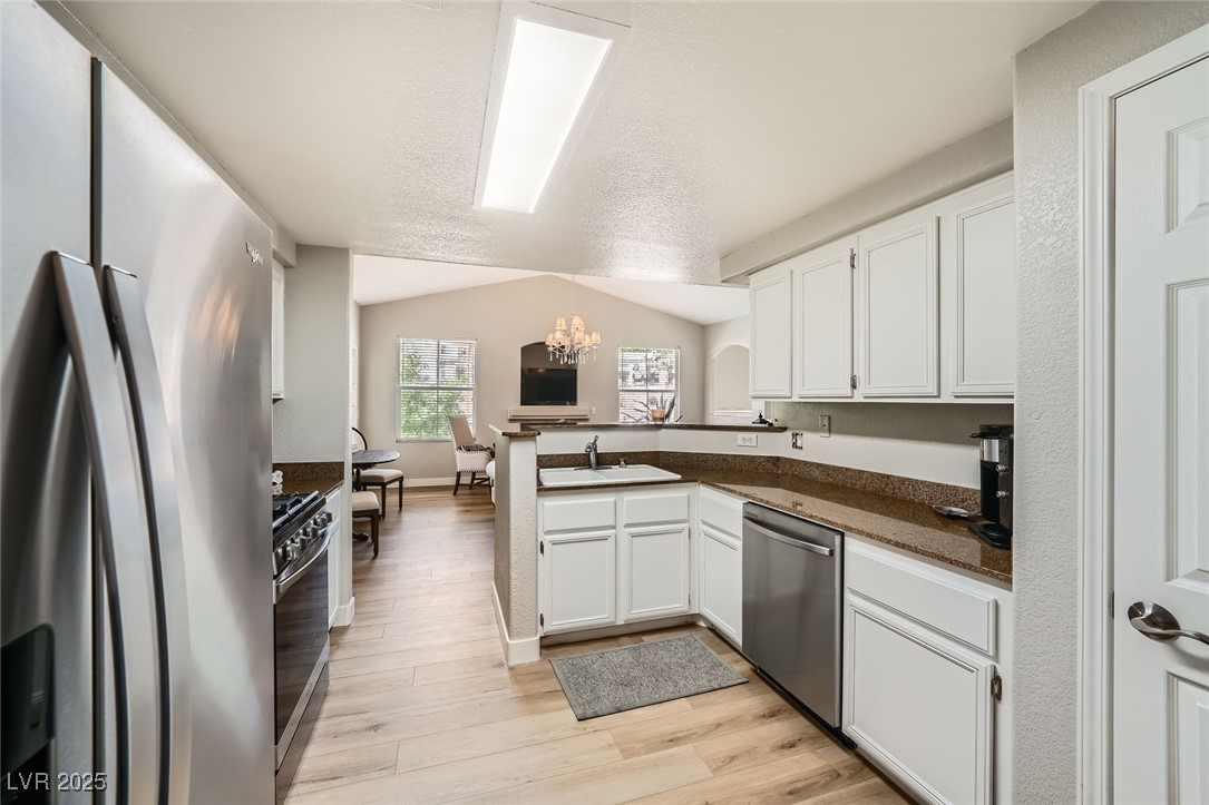 10550 West Alexander Road, Unit 2179 Las Vegas, NV 89129 - Photo 7 of 28 Kitchen with white cabinets, stainless steel appliances, a sink, dark countertops, and a chandelier