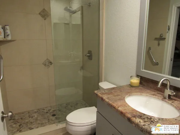 a bathroom with a granite countertop sink a toilet and shower