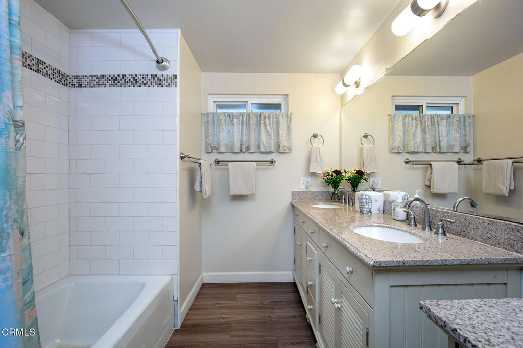 1235 Capri Way Oxnard, CA 93035 - Photo 17 of 21 a bathroom with a granite countertop sink a mirror a bathtub and shower