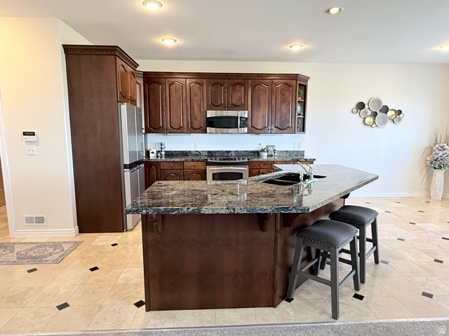 1562 Fairway Ridge Road Draper, UT 84020 - Photo 12 of 60 Kitchen featuring an expansive island with a dark granite countertop, a double basin sink, and integrated seating