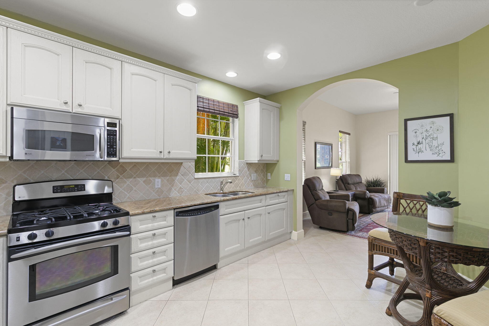 9066 Cascada Way, Unit 101 Naples, FL 34114 - Photo 15 of 51 a kitchen with stainless steel appliances granite countertop a stove top oven a sink a dining table and chairs with white cabinets