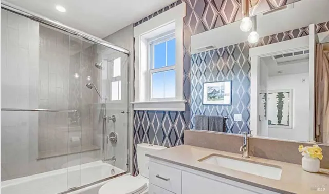 a bathroom with a granite countertop sink a toilet and shower