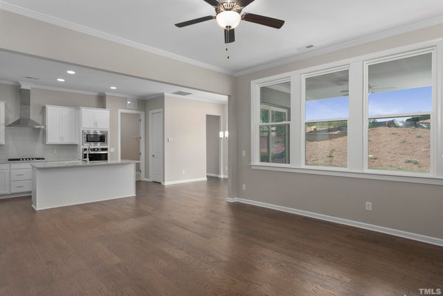 a view of an empty room with kitchen and window