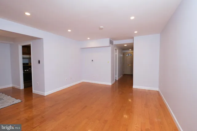 an empty room with wooden floor and entrance to other room