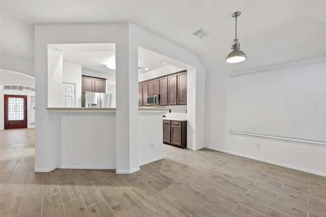 an empty room with wooden floor and a kitchen