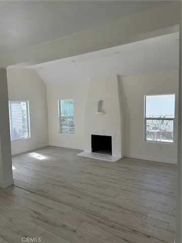 a view of an empty room with window and wooden floor