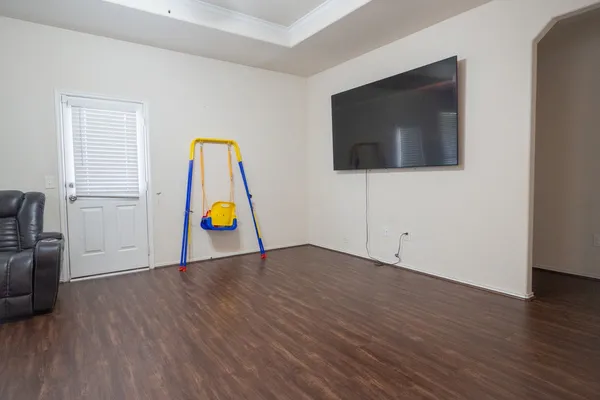 a view of an empty room with wooden floor and cabinet