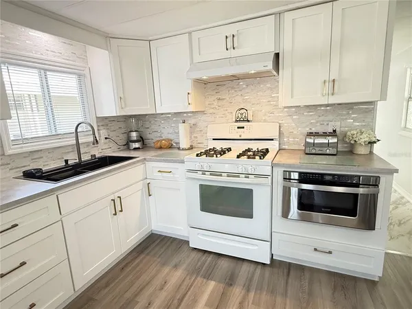 a kitchen with granite countertop white cabinets and white appliances