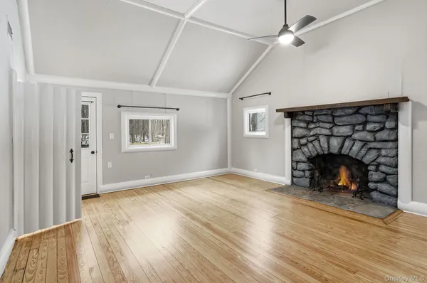 an empty room with wooden floor fireplace and windows