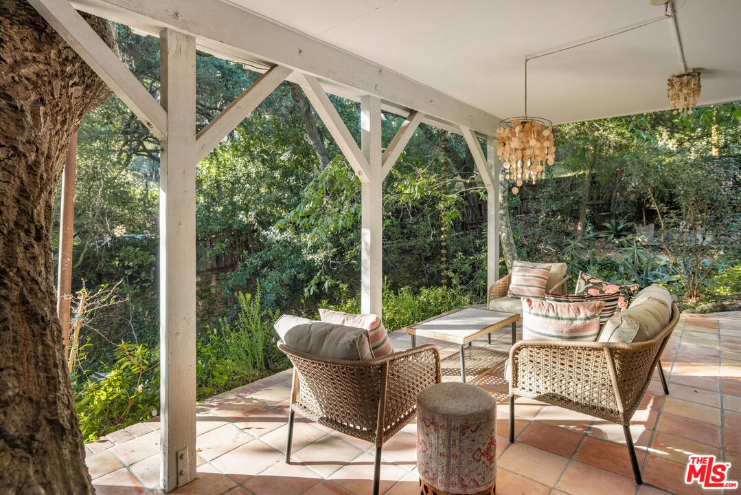 21714 Encina Road Topanga, CA 90290 - Photo 23 of 45 a view of a patio with a table chairs and a floor to ceiling window