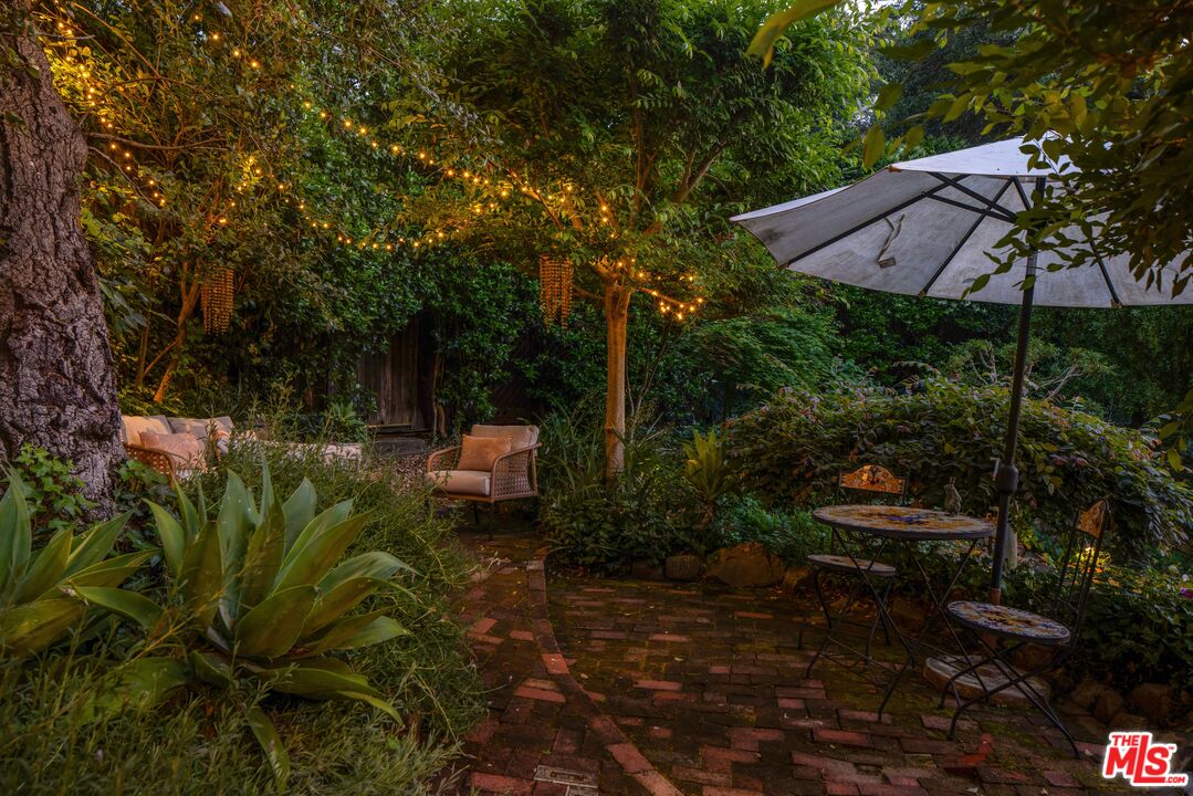 21714 Encina Road Topanga, CA 90290 - Photo 37 of 45 a backyard of a house with table and chairs under an umbrella