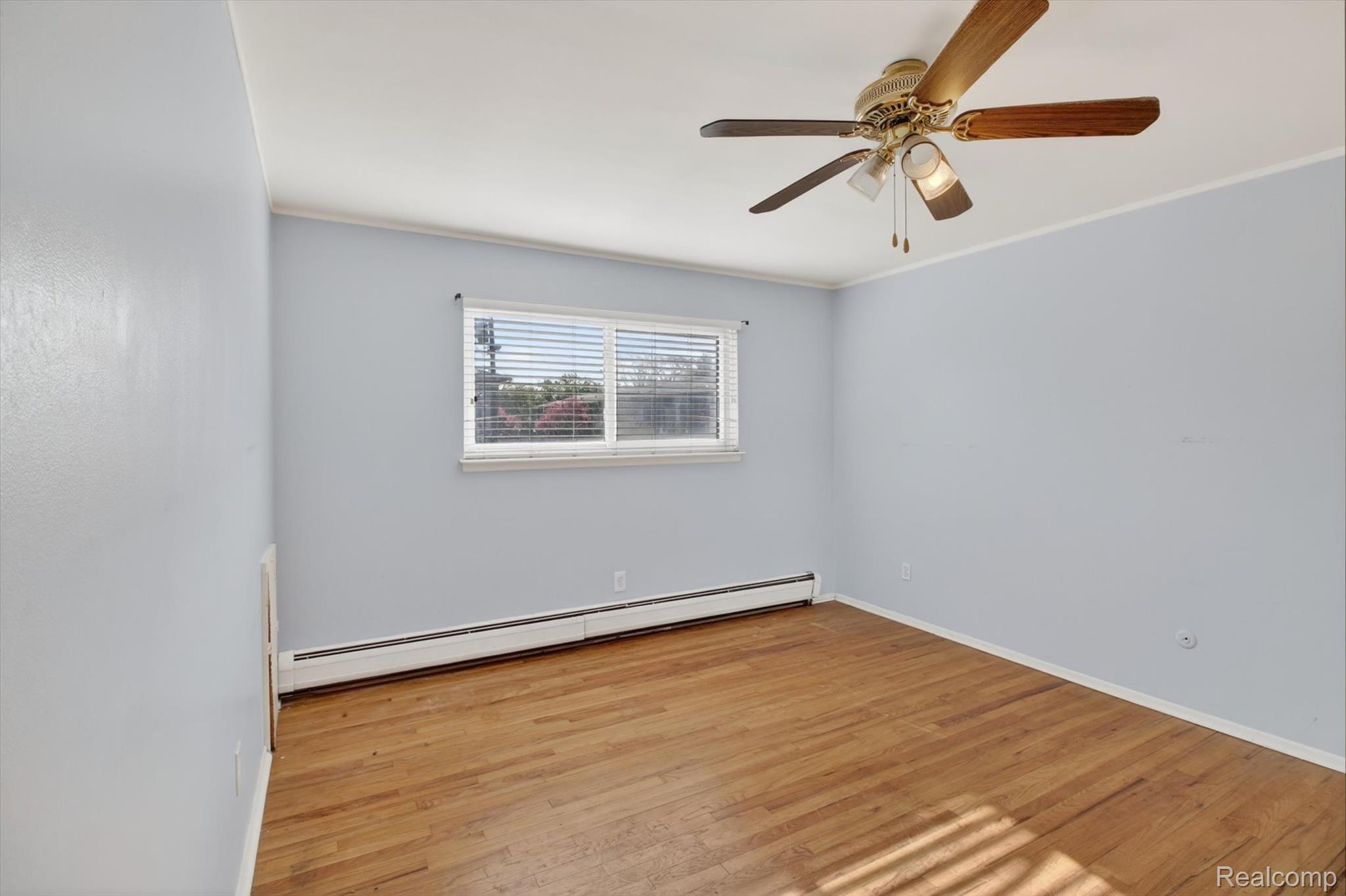 25301 Five Mile Road, Unit 109 Redford, MI 48239 - Photo 19 of 22 Unfurnished room with baseboard heating, light wood-style floors, ornamental molding, and a ceiling fan