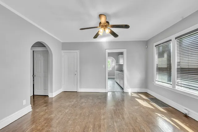 a view of empty room with wooden floor and fan