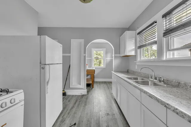 a hallway with sink a mirror and a wooden floor