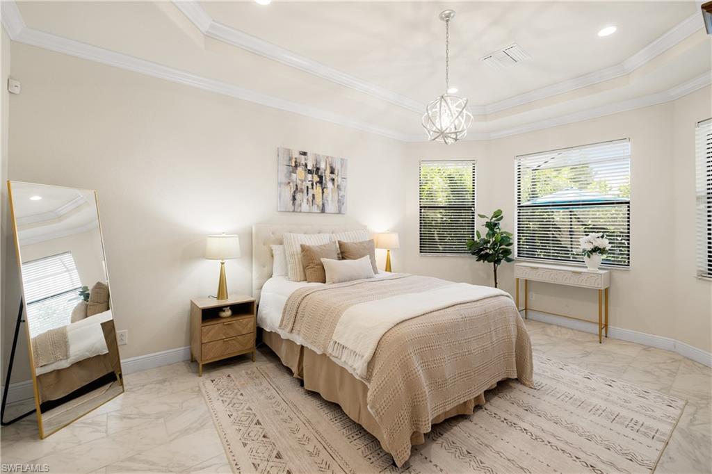 10137 Florence Circle Naples, FL 34119 - Photo 15 of 42 a bedroom with a large bed and a chandelier