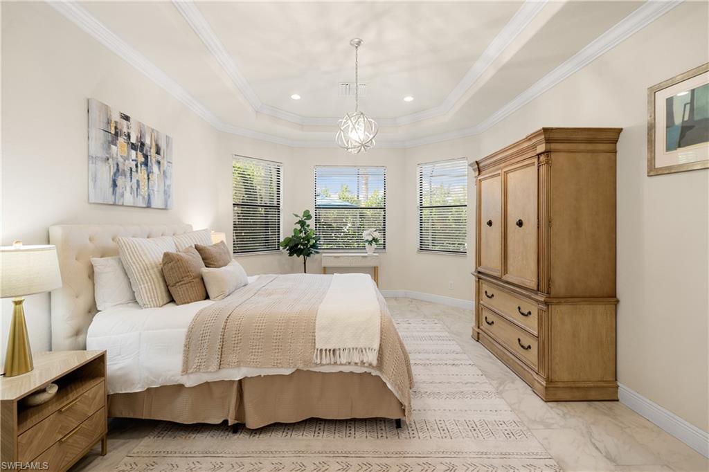 10137 Florence Circle Naples, FL 34119 - Photo 16 of 42 a spacious bedroom with a bed a dresser and painting on the wall