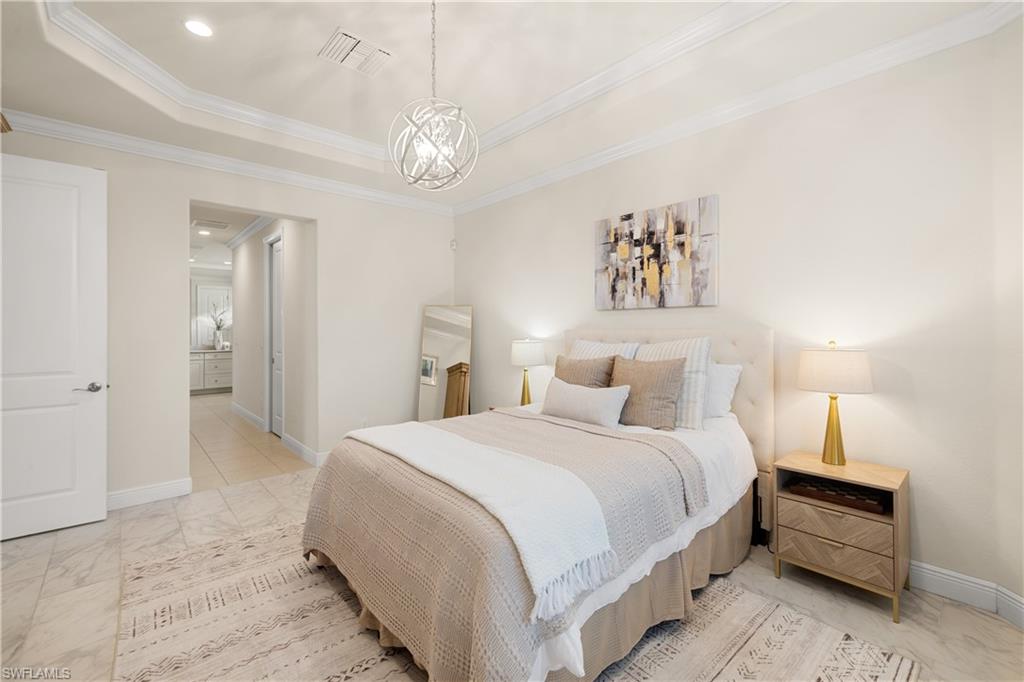 10137 Florence Circle Naples, FL 34119 - Photo 17 of 42 a spacious bedroom with a bed and a chandelier