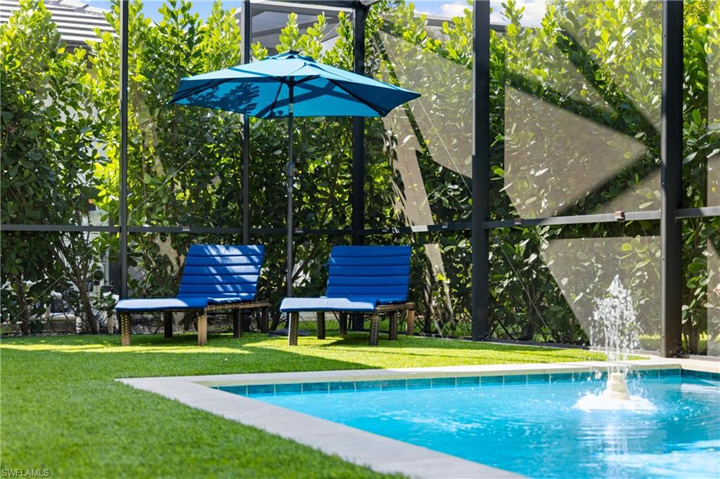 10137 Florence Circle Naples, FL 34119 - Photo 34 of 42 a view of a swimming pool with a table and chairs under an umbrella