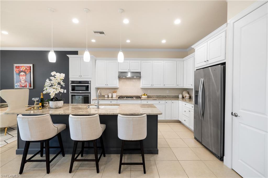 10137 Florence Circle Naples, FL 34119 - Photo 7 of 42 a kitchen with a dining table chairs refrigerator and cabinets