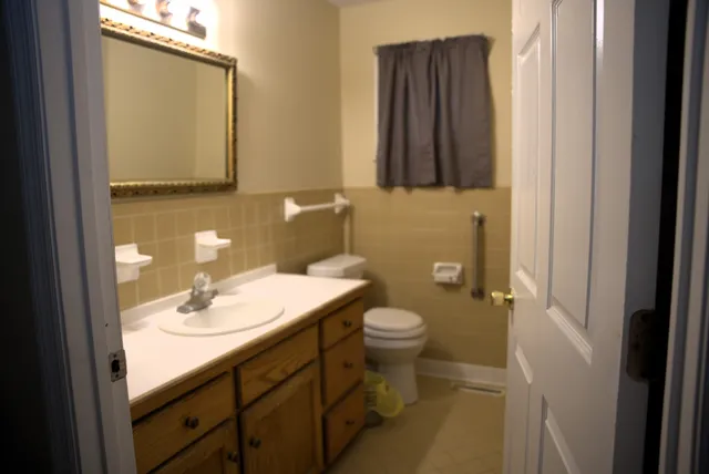 a bathroom with a granite countertop sink toilet and mirror