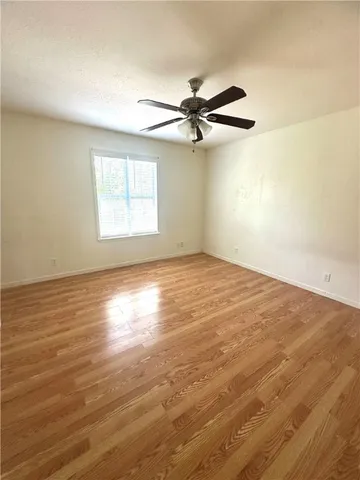 an empty room with wooden floor fan and windows