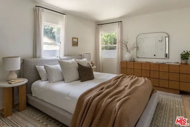 a bedroom with a bed a mirror and window