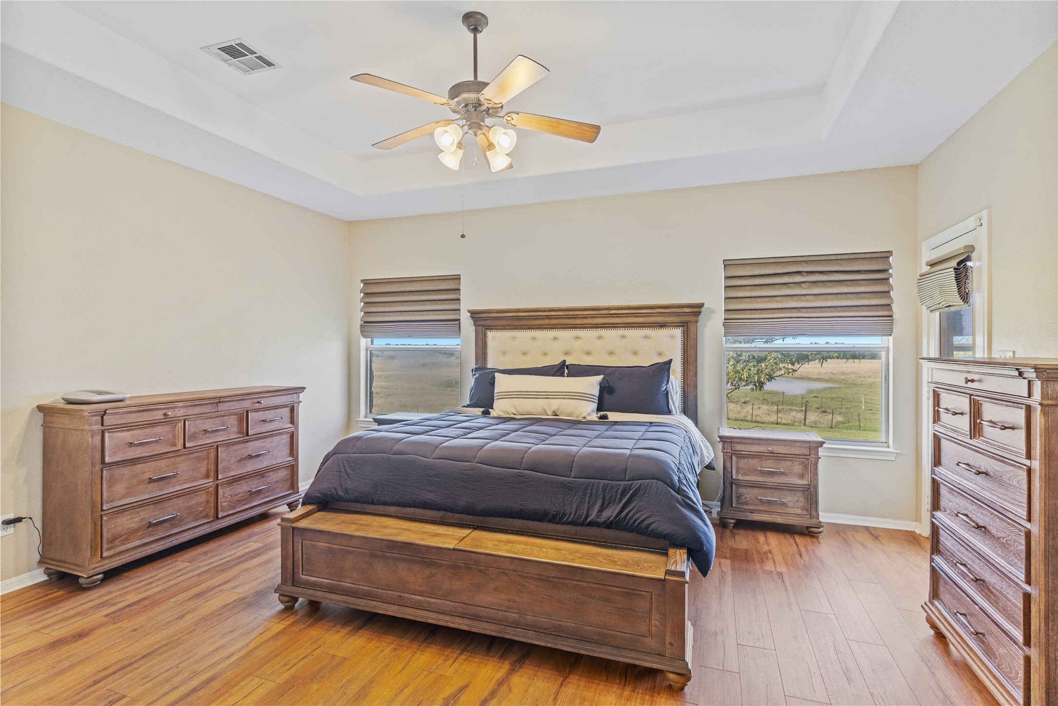 20145 Janak Road Coupland, TX 78615 - Photo 15 of 40 The spacious primary suite features rich hardwood floors, private access to the back porch, and breathtaking views overlooking the property's rolling landscape.