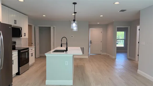 a kitchen with stainless steel appliances granite countertop a refrigerator a stove and a wooden floors