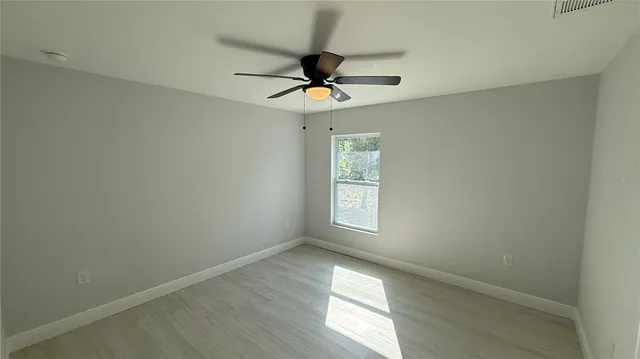 an empty room with windows and fan