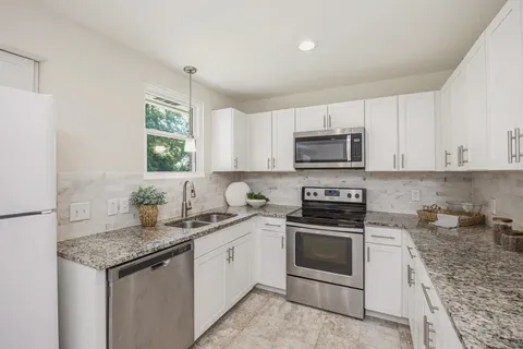 a kitchen with stainless steel appliances granite countertop a sink stove and refrigerator