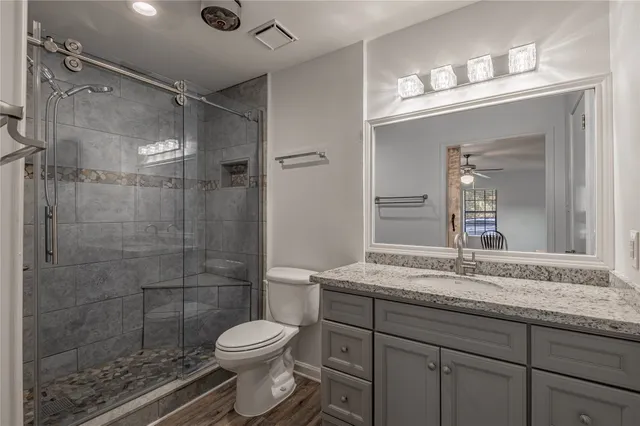 a bathroom with a granite countertop sink a toilet and shower