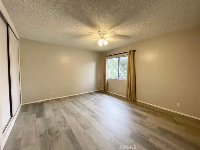 an empty room with wooden floor fan and windows